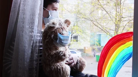 Boy is sitting at the window. the boy adjusts the mask to the bear Stock Footage 128430150