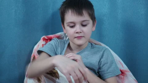 A boy sitting wrapped in a blanket measures the temperature with a thermometer Stock Footage 144262669