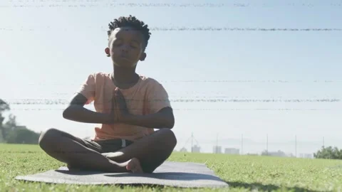 Boy sitting on yoga mat, taking breath and initiating stretch while color bands Stock Footage 333318523