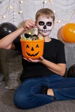 A boy in skeleton makeup pulls out candy from a Halloween party. Stock Photos