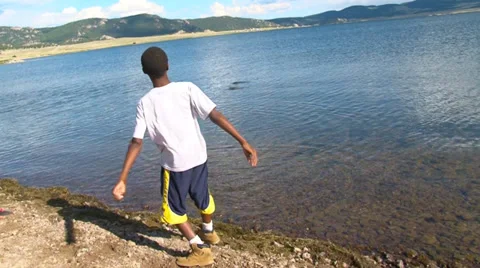 Boy skipping rocks on lake. Stock-Footage 27896130
