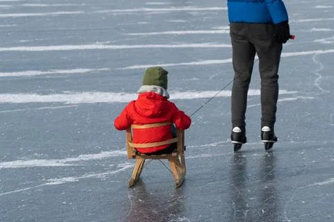 Boy on sled pulled bij father on ice Stock Photos