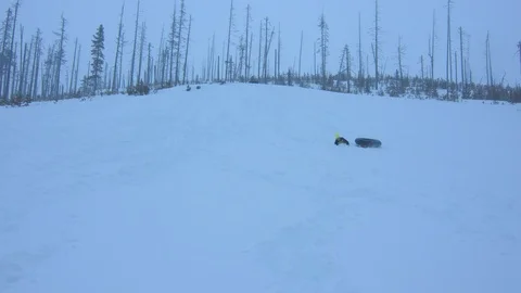 Boy Sledding Down a Hill and Falling off of the Innertube in Slow Motion Stock Footage 102928674