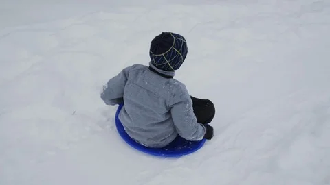 Boy sleds down hill past mother in snow in Germany Stock Footage 121754095