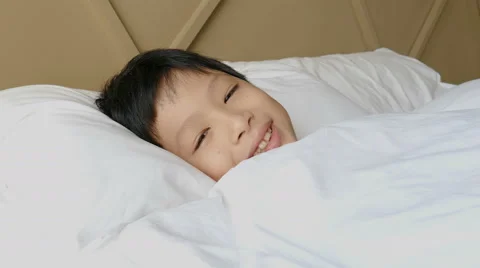 Boy sleeping on bed and smiles after wake up Stock Footage 61311978