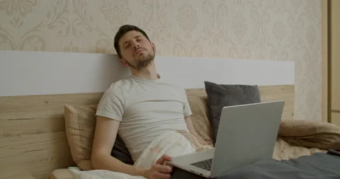 The boy is sleeping in bed with the computer in his arms Stock Footage 196000371