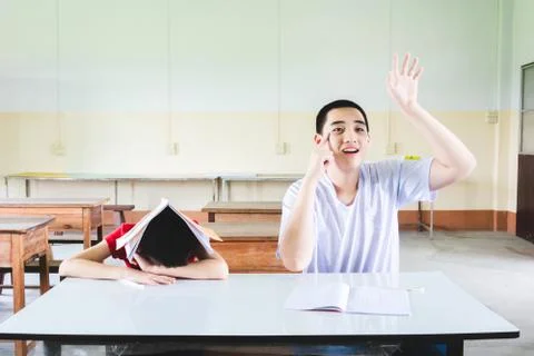 Boy is sleeping in class but another on hand up to answer the question Photos