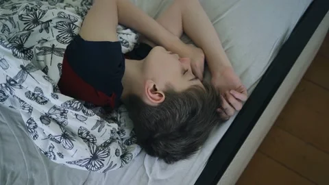 The boy sleeps on the bed under a blanket Stock Footage 154370283