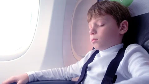 Boy sleeps on a plane next to the window. Side view. Stock Footage 116590228
