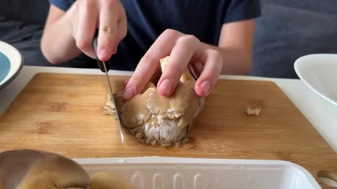 Boy is slicing mushrooms on cutting board close-up, unrecognizable, part of Stock Footage 337338976