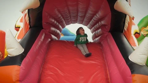 Boy sliding on Bouncy Castle slide Stock Footage 113456980