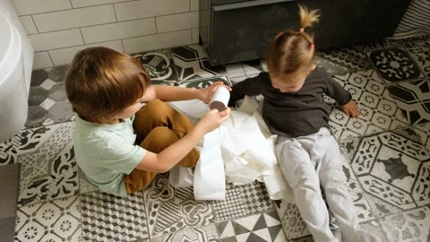 Boy with small sister has fun with toilet paper in bathroom Stock Footage 142440473