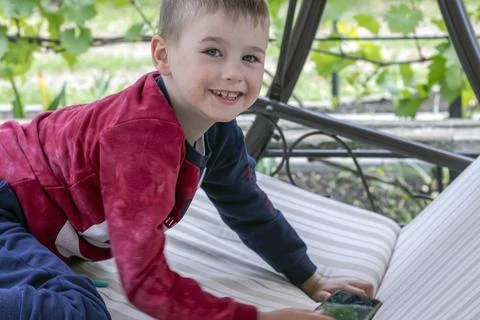 Boy with smartphone on garden sofa in spring in the garden. Stock Photos