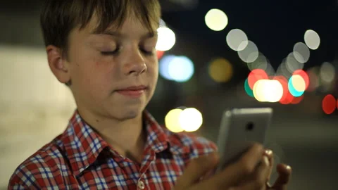 Boy with a smartphone in hand on the background of night city lights. Video stock 93323439