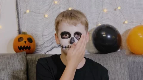 Boy smears makeup on his face with his hands after the celebration of Halloween Stock Footage 218623777