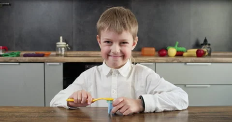 Boy smiles broadly while holding toothbrush and model of teeth Stock Footage 314721565