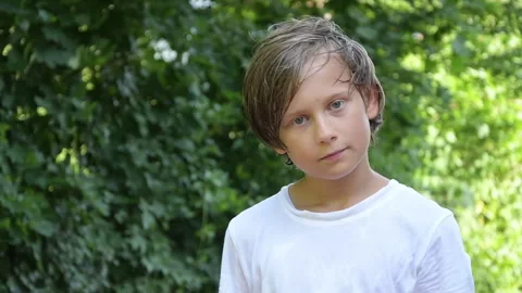 A boy smiling in the background of nature in summer, looking at the camera, slow Stock Footage 246383827
