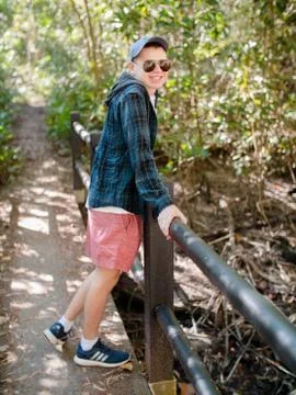 Boy smiling in rain forest while leaning on hand rail Stock Photos