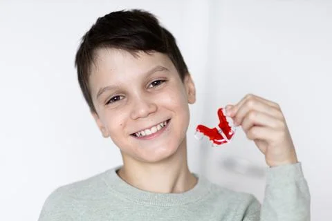 Boy smiling with tooth retainers in hand. Concept of crooked teeth correction Stock Photos
