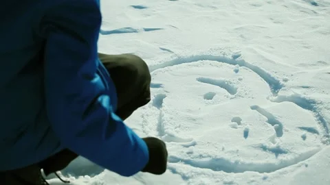 Boy in the Snow Draws A Smiley Face With His Hand. The concept of Friendship Stock Footage 153325336