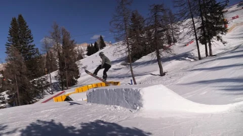 Boy on Snowboard doing a Big Jump on a Platform made of Snow at the SnowPark Video stock 173439172