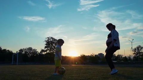 Boy soccer player playing with his pregnant mother with a ball in the stadium Stock Footage 197742214