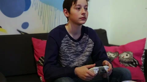 Boy on Sofa Playing in Computer Game with Joystick Video stock 58238321