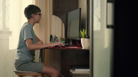 A boy solves interactive exercises using a computer at home while sitting at a Stock Footage 236640343