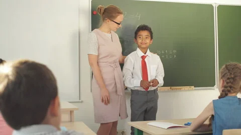 Boy solving addition and subtraction on board. schoolboy writing solution of Stock Footage 100868856