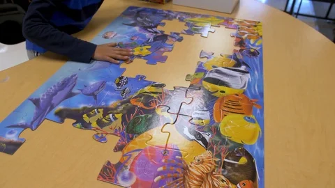 A boy solving puzzle in school, wide shot Video stock 93899723