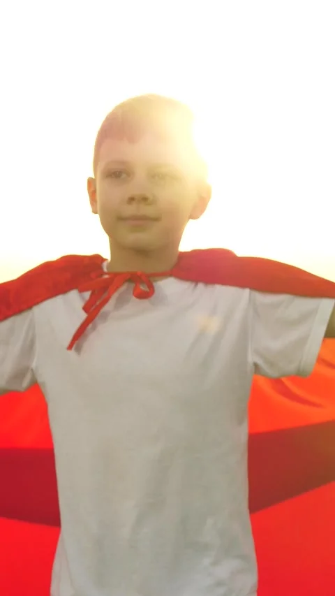 Boy son child superhero game running park field sunset grass victory red cloak Stock Footage 280947156