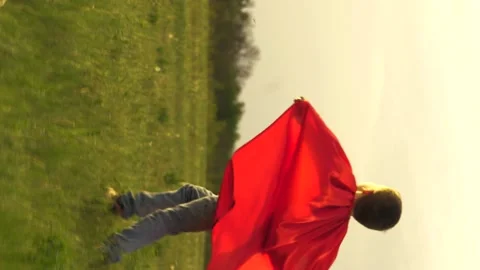 Boy son child superhero game running park field sunset grass victory red cloak Stock Footage 301238256
