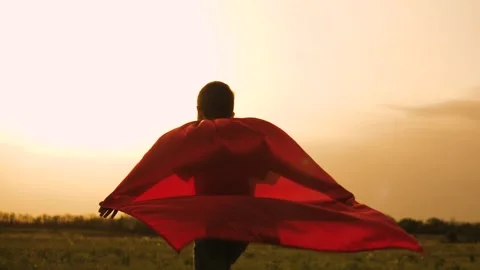 Boy son child superhero game running park field sunset grass victory red cloak Stock Footage 303077584