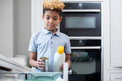 Boy Sorting Recycling Into Kitchen Bin At Home Stock Photos