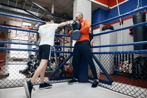 Boy sparring with coach on the ring Stock Photos