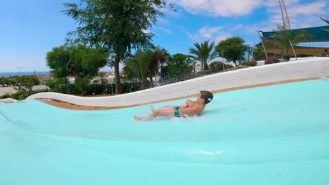 Boy speeding down sliding in a water slide at Water Amusement Park on summer. Stock Footage 135314620