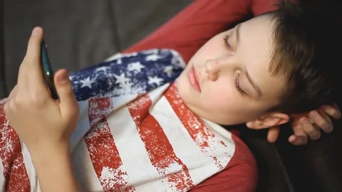 Boy Spends Time with the Phone while Lying on the Couch. Stock Footage 147945405
