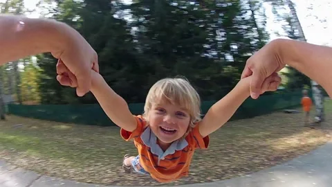 Boy is spinning in a circle by father. View from the hands of the father. Stock Footage 267250695