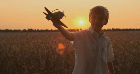 Boy is spinning with a plane in his hands. Boy is playing with a wooden airpl Stock Footage 119004229