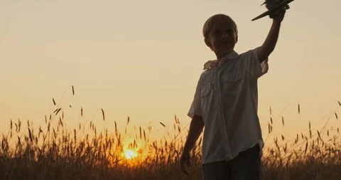 Boy is spinning with a plane in his hands. Boy is playing with a wooden airpl Stock Footage 120503447