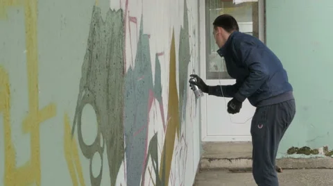 Boy with spray drawing graffiti or mural on building wall, street graffiti art. Stock Footage 57126700