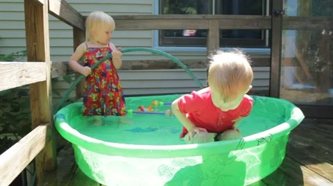 Boy squats and then jumps in the kiddie pool Stock Footage 40027452