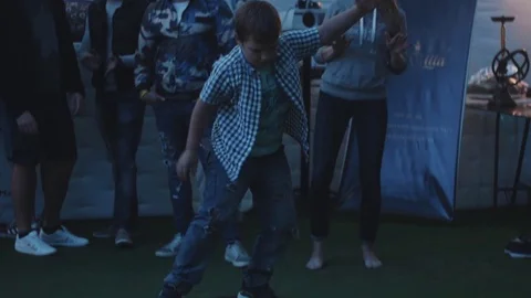 Boy squats while balancing board on a cylinder during festival and gets applause Stock Footage 71812124