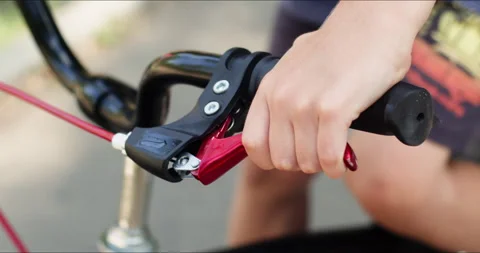 Boy squeezes brake levers on handlebars learning biking Stockbeeldmateriaal 273780400