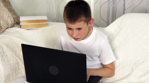 Boy squinting eyes and looking to laptop at home. Stock Footage 154233755