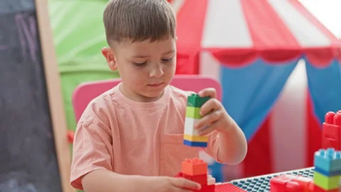 Boy stacking blocks with hand holding a tall tower in a colorful play area .. Stock Footage 339159304