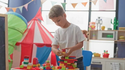 Boy stacking colorful plastic blocks with hands in a playroom inside a brig.. Stock Footage 339171718