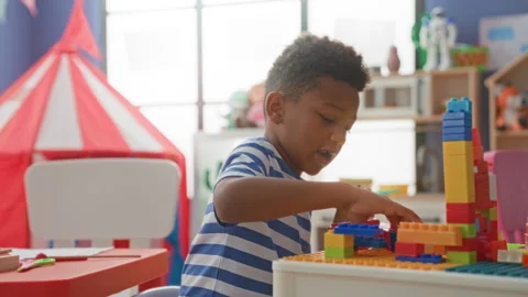 Boy stacking colorful plastic blocks with hands at a low table in a bright .. Stock Footage 339243555