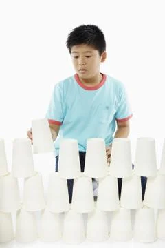 Boy stacking up disposable cups Stock Photos