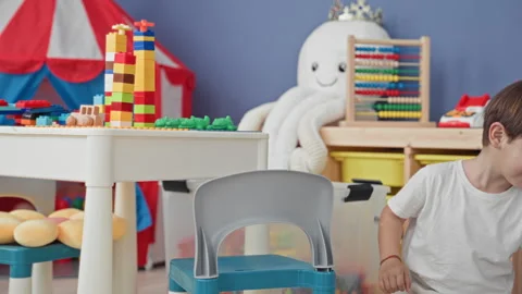 Boy stacking plastic blocks on a low table in a colorful playroom with tent.. Stock Footage 339248464